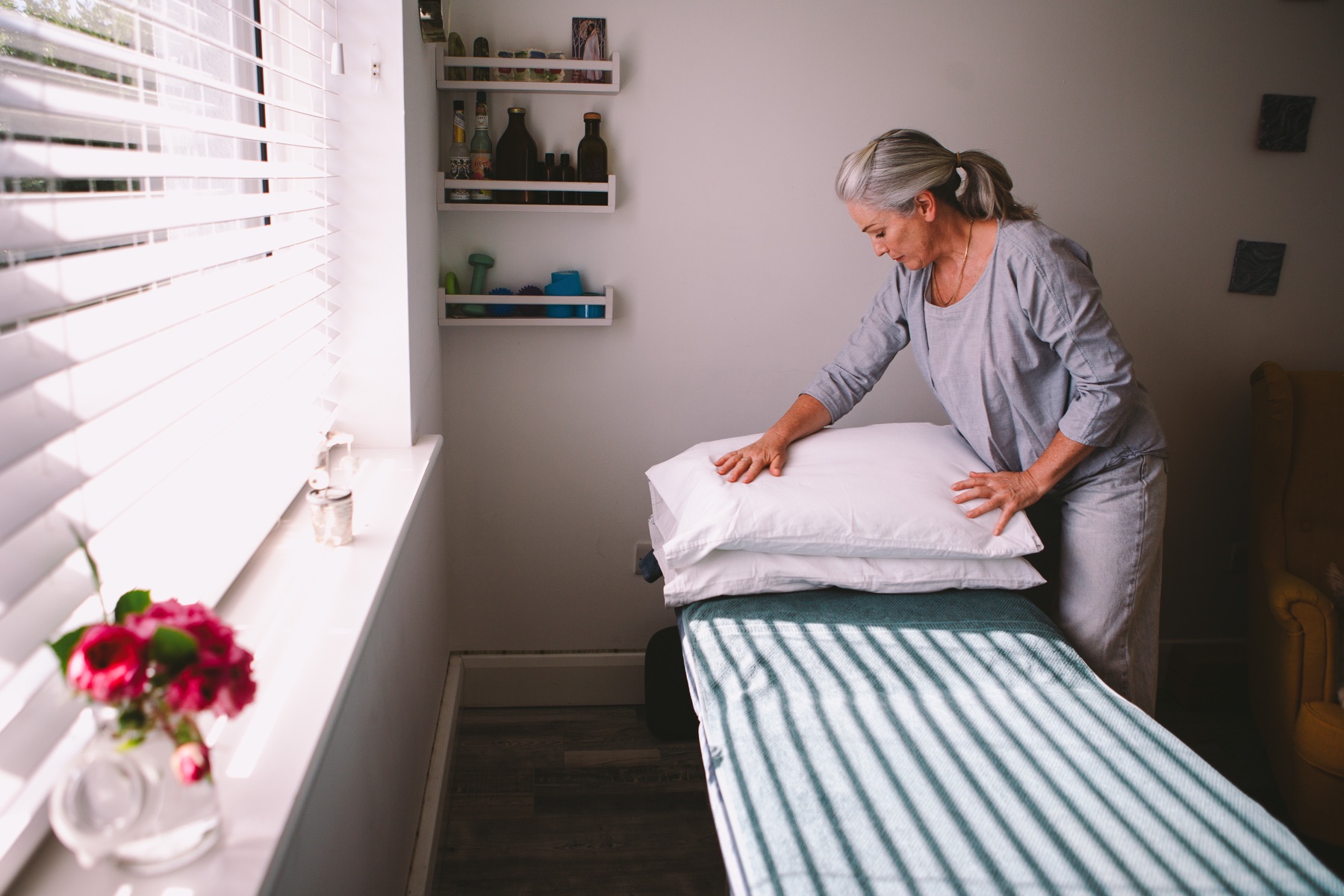 Ruth preparing the treatment bed, arranging pillows by the window