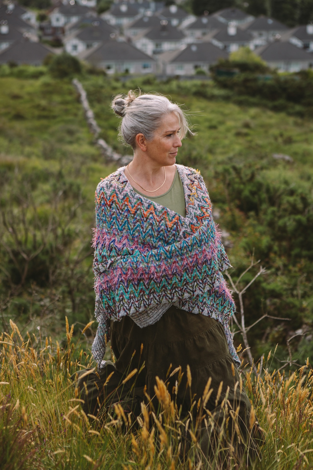 Ruth standing in a grassy hillside field, homes visible in the distance