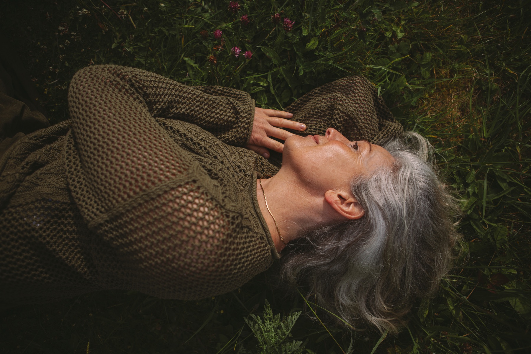 A woman resting in tall grass, restful and at ease